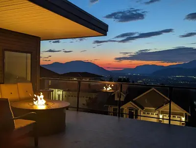 a balcony with a table and a sunset at Mountain Retreat with Views, Hot Tub, Games & AC in Chilliwack