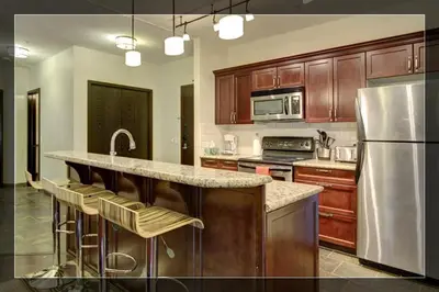 a kitchen with wooden cabinets and a stainless steel refrigerator at Luxury 2 Bedroom 1Pullout Kitchenette Grand Rockies Resort Hot Tub Pool Mountain View in Canmore