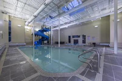 an indoor swimming pool with a slide in a building at Luxury 2 Bedroom 1Pullout Kitchenette Grand Rockies Resort Hot Tub Pool Mountain View in Canmore