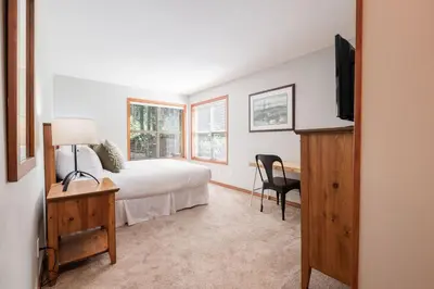 a bedroom with a bed and a desk and a television at Arrowhead Point by Outpost Whistler in Whistler