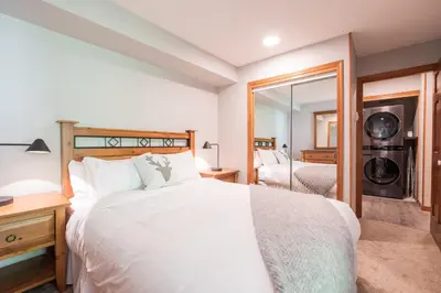 a bedroom with a large white bed and a mirror at Arrowhead Point by Outpost Whistler in Whistler