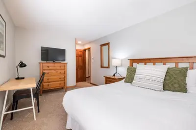 a bedroom with a bed and a desk and a television at Arrowhead Point by Outpost Whistler in Whistler