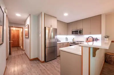 a kitchen with white cabinets and a stainless steel refrigerator at Arrowhead Point by Outpost Whistler in Whistler
