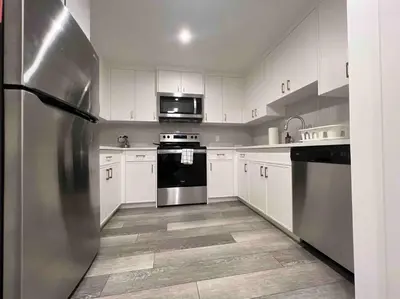 a stainless steel refrigerator in a kitchen with white cabinets at 2BR Suite, Private Entry, Full Kitchen, Washer & Dryer, Free Parking, Smart TV with Netflix, High-Speed Wi-Fi, Self Check-In, Near Banff National Park in Calgary