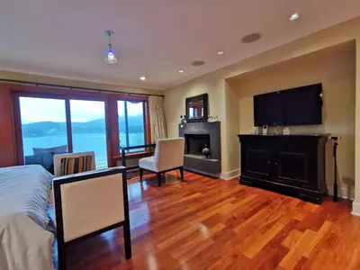 a bedroom with a bed and a fireplace and a television at Deep Cove Stunning Waterfront Whole House in North Vancouver