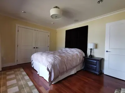 a bedroom with a bed and a dresser and a lamp at Deep Cove Stunning Waterfront Whole House in North Vancouver