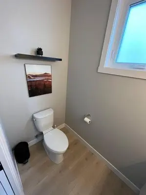 a white bathroom with a toilet and a window at Ocean View Oasis in Campbell River
