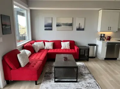 a living room with a red couch and a table at Ocean View Oasis in Campbell River