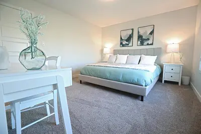 a bedroom with a bed and a table with a vase on it at Stylish Home with AC, 3 King Beds, Garage, Disney in Edmonton