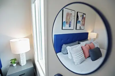 a mirror in a room with a bed with pillows at Stylish Home with AC, 3 King Beds, Garage, Disney in Edmonton