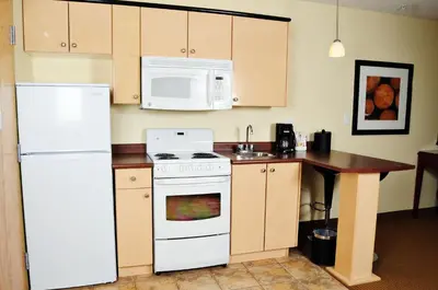 a kitchen with a white refrigerator and a microwave at Trend Mountain Hotel & Conference Centre in Tumbler Ridge