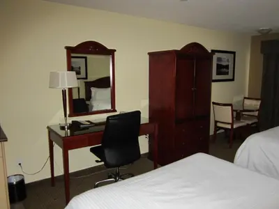 a hotel room with a desk and a mirror at Trend Mountain Hotel & Conference Centre in Tumbler Ridge