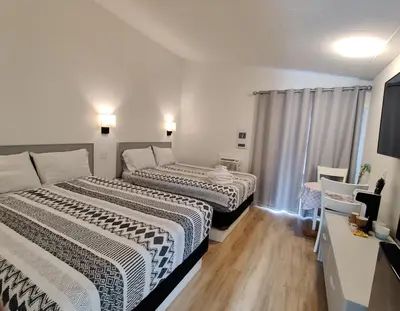 two beds in a small room with a window at Destination Inn Cache Creek in Cache Creek