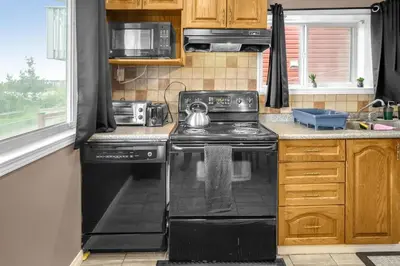 a kitchen with a black stove and a microwave at 52-3 Bed Suite On Lake Central Ac By Airport in Calgary