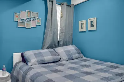 a blue bedroom with a bed with a blue wall at 52-3 Bed Suite On Lake Central Ac By Airport in Calgary