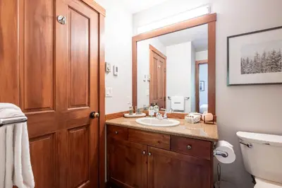 a bathroom with a sink and a toilet and a mirror at Taluswood Bluffs by Outpost Whistler in Whistler