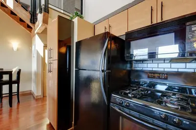 a kitchen with a black refrigerator and a stove at Unique Style 2 Bedroom 2 Bath Condo In Old Town Victoria in Victoria