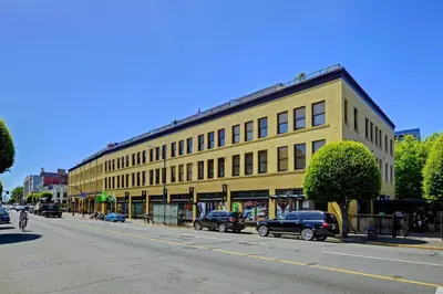 a large yellow building with cars parked in front of it at Unique Style 2 Bedroom 2 Bath Condo In Old Town Victoria in Victoria