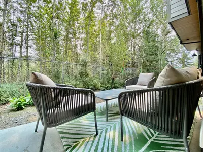 a patio with two chairs and a table with pillows at Enchanted Mountain Getaway in Canmore