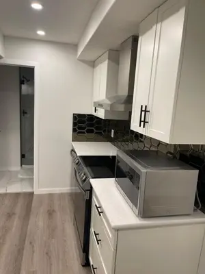 a kitchen with white cabinets and a microwave at Grande Villa in Calgary