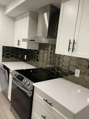 a kitchen with white cabinets and a stove top oven at Grande Villa in Calgary