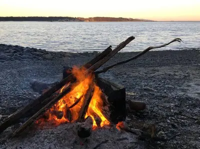 a campfire on the beach with the ocean in the background at Saanichton Waterfront 2BR suite with superb views in Saanichton