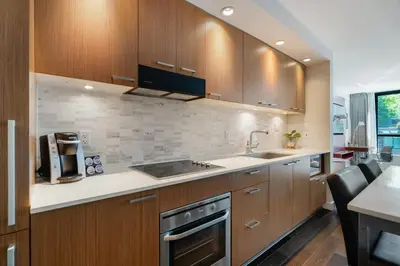 a kitchen with wooden cabinets and a stove top oven at Level Vancouver Yaletown Seymour in Vancouver