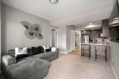a living room with a couch and a clock on the wall at Modern Basement Gem: 2 BR Retreat in Calgary