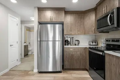 a stainless steel refrigerator in a kitchen with wooden cabinets at Modern Basement Gem: 2 BR Retreat in Calgary