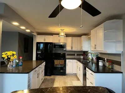 a kitchen with white cabinets and a black refrigerator at Grie hunting quite room! in Calgary
