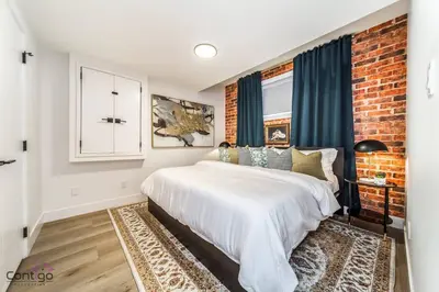 a bedroom with a white bed and a brick wall at Luxe New York Style Bsmt Suite, Near DT & WEM, King Bed, WiFi in Edmonton