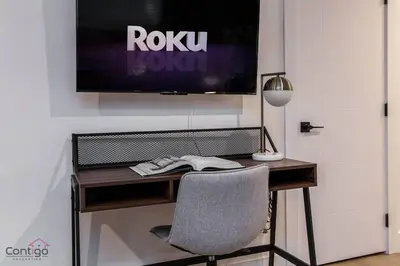 a desk with a chair and a television on a wall at Luxe New York Style Bsmt Suite, Near DT & WEM, King Bed, WiFi in Edmonton