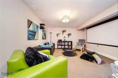 a living room with green chairs and a white screen at Cozy 3BD w/AC, Patio, Theatre Room, 15 min to DT in Edmonton