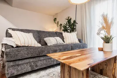 a living room with a couch and a wooden table at Cozy 3BD w/AC, Patio, Theatre Room, 15 min to DT in Edmonton