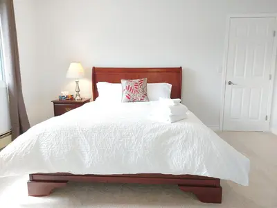 a bedroom with a white bed with a wooden headboard at Tranquil Retreat Spacious 2-Bedroom on the 2nd Floor in Kelowna