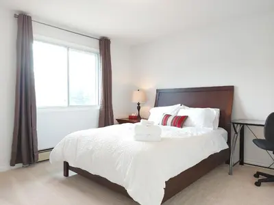 a bedroom with a white bed with a window at Tranquil Retreat Spacious 2-Bedroom on the 2nd Floor in Kelowna