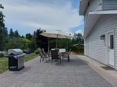 a patio with a table and chairs and an umbrella at Tranquil Retreat Spacious 2-Bedroom on the 2nd Floor in Kelowna