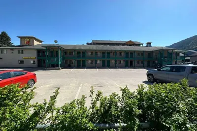 a large building with cars parked in a parking lot at Super 8 by Wyndham Sicamous in Sicamous