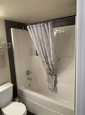 a bathroom with a tub and a toilet and a shower at Chris's Cozy Condo Times Square Rogers Place Edmonton in Edmonton