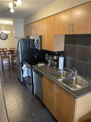 a kitchen with a sink and a stove and refrigerator at Chris's Cozy Condo Times Square Rogers Place Edmonton in Edmonton