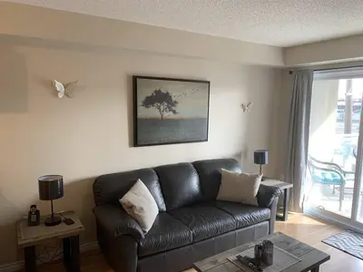 a living room with a black leather couch and butterflies at Chris's Cozy Condo Times Square Rogers Place Edmonton in Edmonton