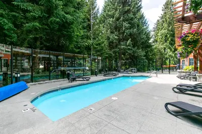 a large swimming pool with chairs around it at Bright Whistler Village Getaway w/ pool & hot tub in Whistler