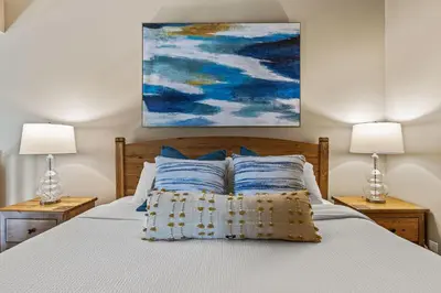 a bedroom with a bed with two lamps and a painting at Top Floor Wolf - Best Views With Pool and Hot tub in Canmore