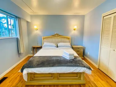 a bedroom with a bed with blue walls and a window at Spacious home 15mins to Downtown in Vancouver