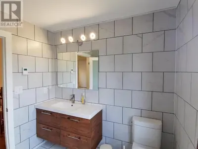 a bathroom with a sink and a toilet and a mirror at The Blue Cottage B&B in Seventy Mile