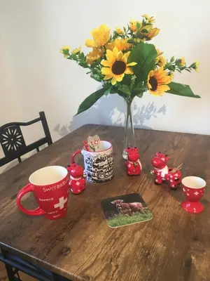 a wooden table with a vase of flowers and two cups at The Blue Cottage B&B in Seventy Mile
