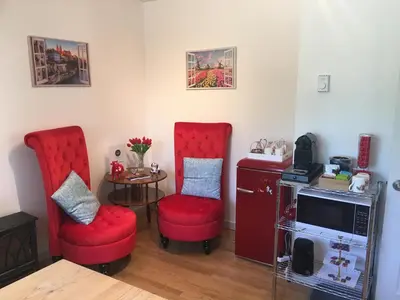 a living room with two red chairs and a small table at The Blue Cottage B&B in Seventy Mile