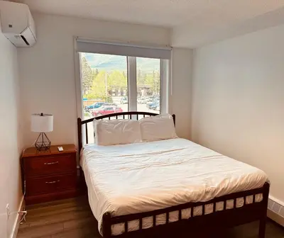 a small bedroom with a bed and a window at unit #203 Cozy Mountain View 1BR in DT in Canmore