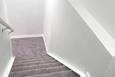 a stairway with white walls and a carpet at Luxurious Comfortable Suite in Airdrie