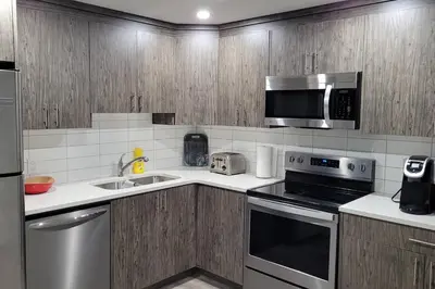 a kitchen with stainless steel appliances and wooden cabinets at Luxurious Comfortable Suite in Airdrie